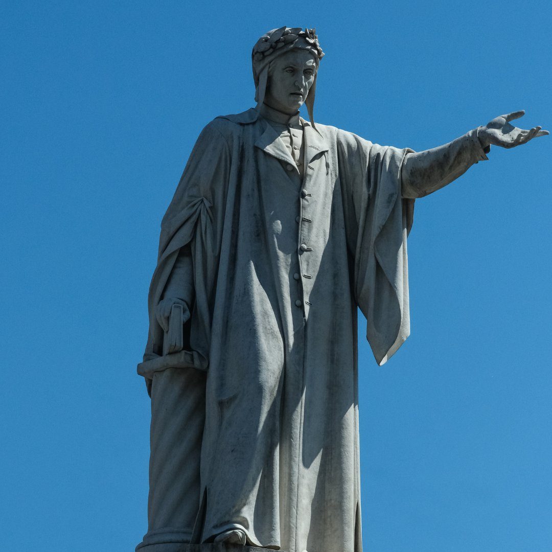 Statua marmorea di Dante Alighieri contro un cielo azzurro in Piazza Dante, Napoli