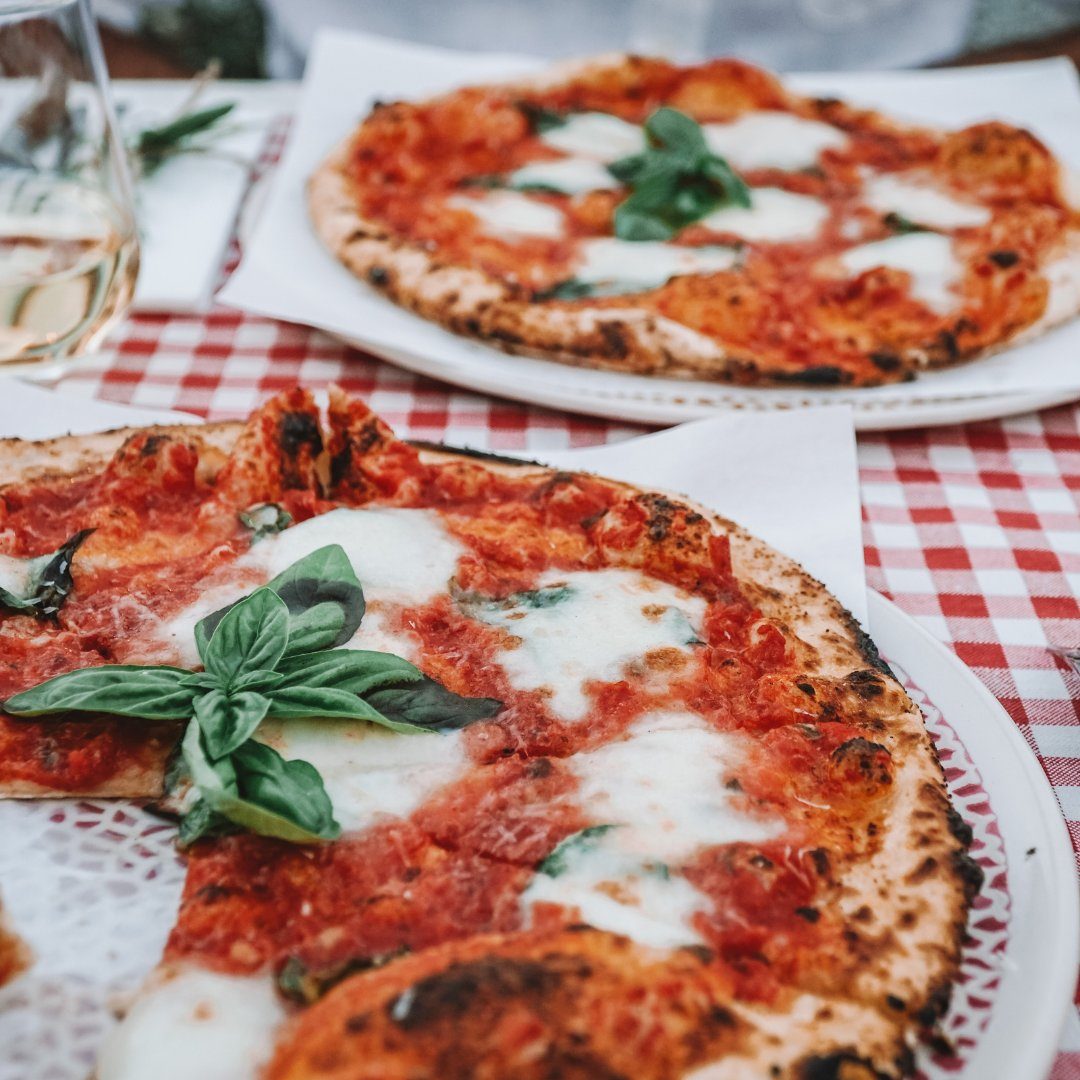 Due pizze margherita napoletane cotte nel forno a legna con basilico su una tovaglia a quadri